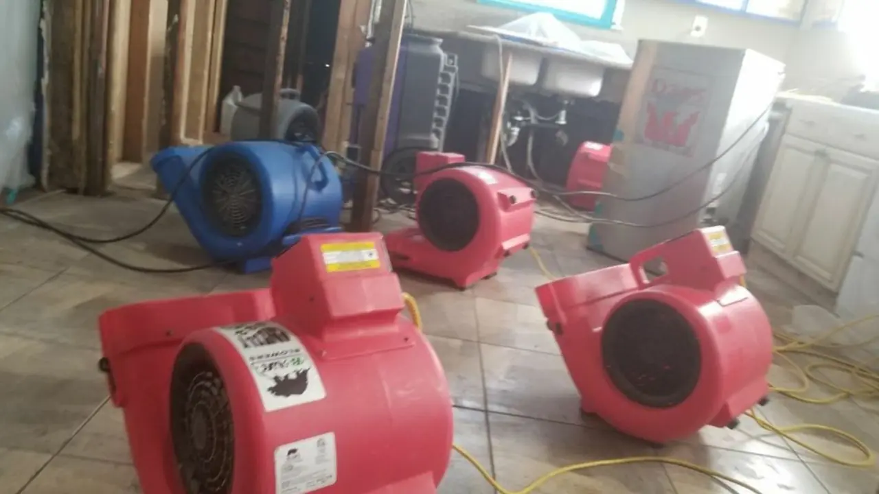 Blue and red air movers set up to dry a tiled floor